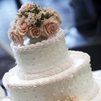 white, two-tiered cake with floral bouquet topper